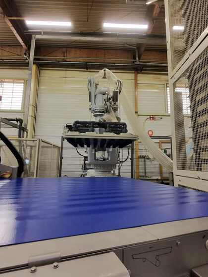Bras robotise avec prehenseur positionne au-dessus du convoyeur bleu, cellule de demoulage robotisee agroalimentaire